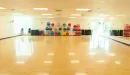 Thumbnail: Large group exercise room. Medicine balls, chairs for senior classes, and other exercise equipment organized on wall. Mirrors along front wall.