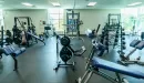 Thumbnail: Weight room featuring benches, machines, free weights, and squat racks throughout room. Large windows to the outside.