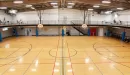 Thumbnail: Gymnasium with multiple hoops. Small bench seats along walls of court. Large indoor track running overhead with machines in corners.