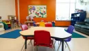 Thumbnail: Child care room with toys, tables and chairs, and rugs. Brightly painted with fun graphics.