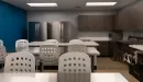 Thumbnail: Community kitchen area with two sets of high, long tables with chairs. Two refrigerators, stove, microwave, and other cooking supplies.