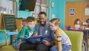 Thumbnail: ymca y club staff reading a book to two boys in the ymca y club before and after school program
