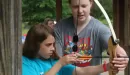 Thumbnail: young woman helping a girl at the archery range