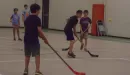 Thumbnail: boys and a counselor playing floor hockey in the gym