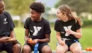 Thumbnail: ymca youth flag football volunteer coach laughing with participants on the bench