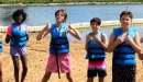 Thumbnail: Campers wearing lifejackets pose at the sandy beach