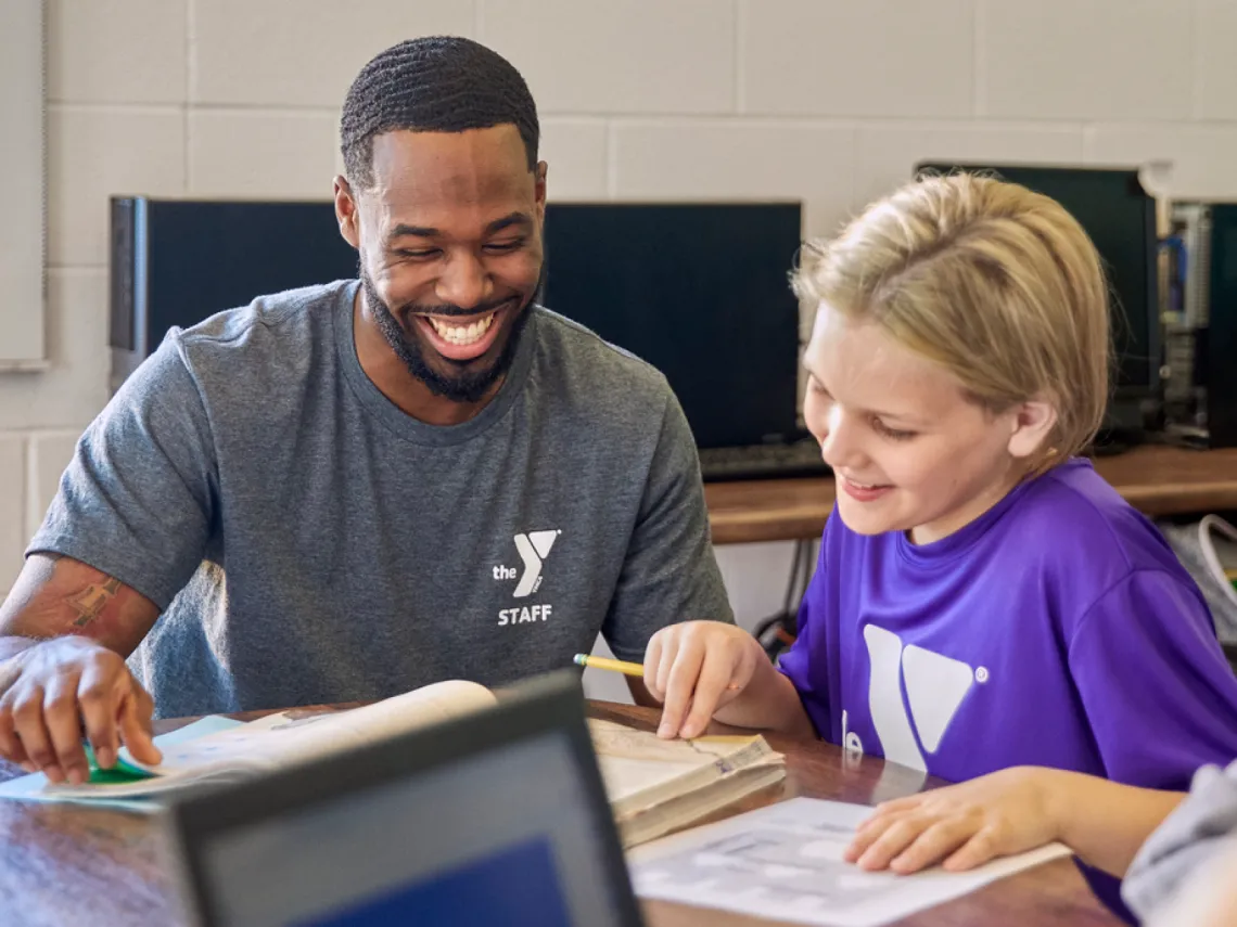 A staff member and student reading at a table