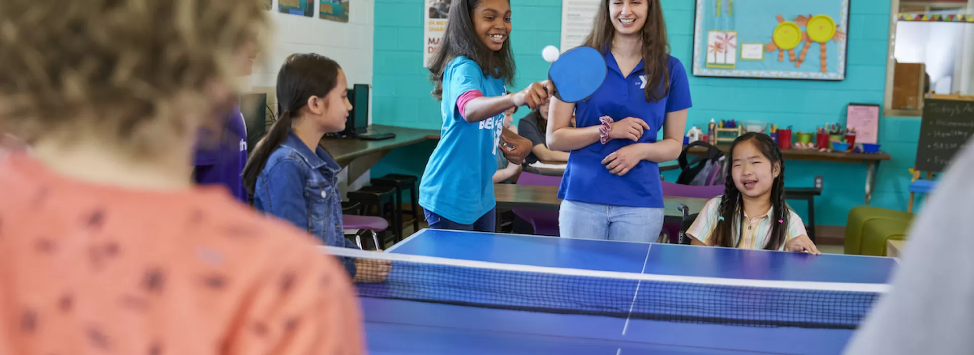 ymca y club staff plays ping pong with y club participants