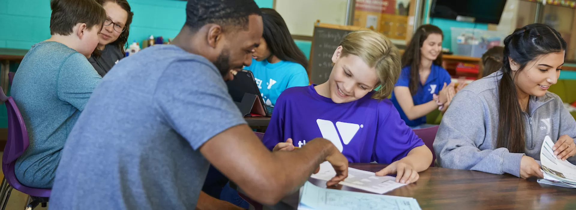 ymca y club staff helps a young student with homework