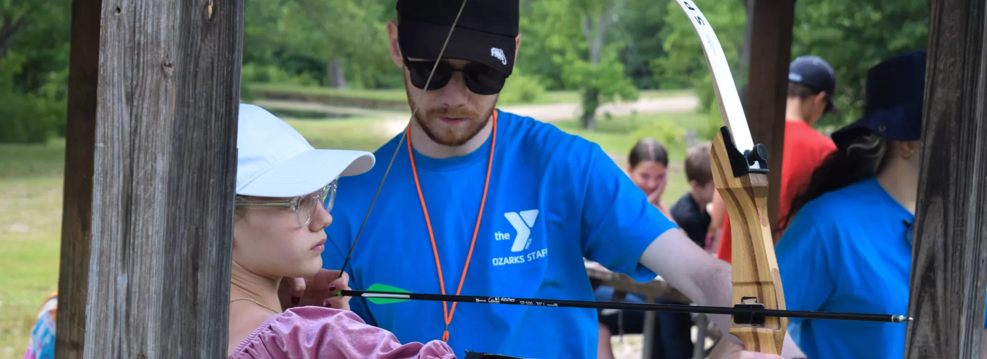 Staff helping camper shoot bow and arrow