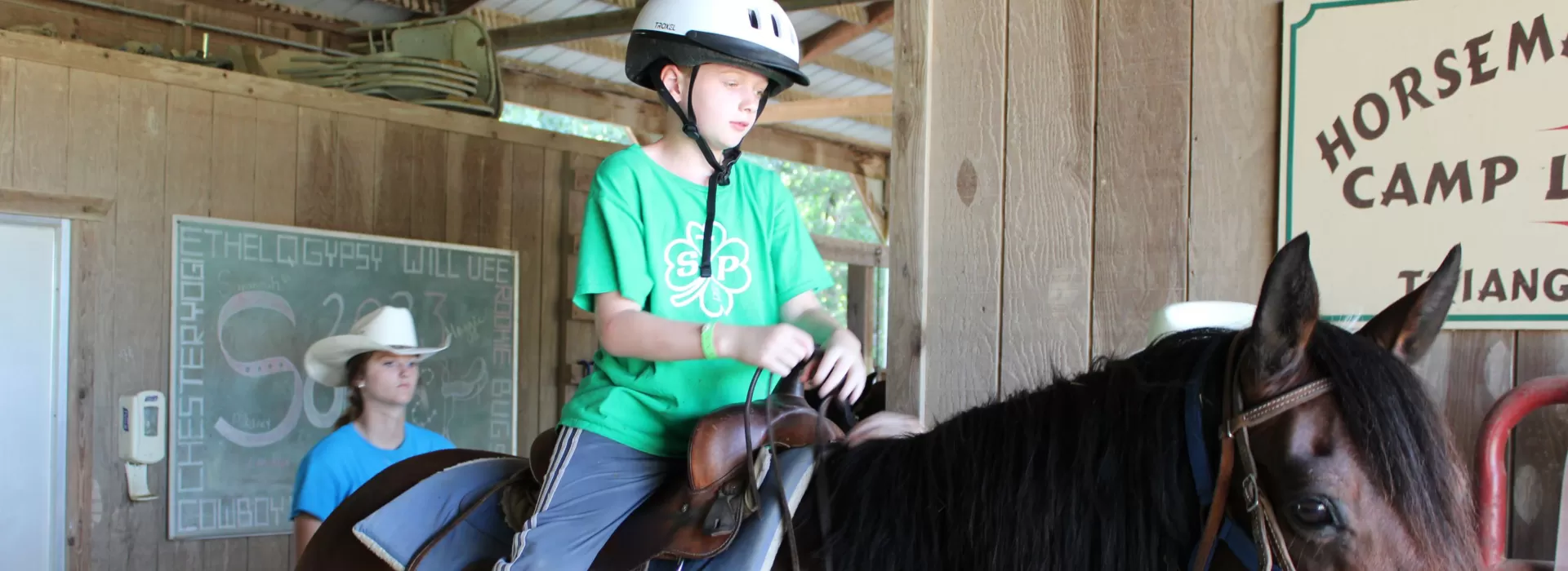 Ranch staff with younger camper on horseback